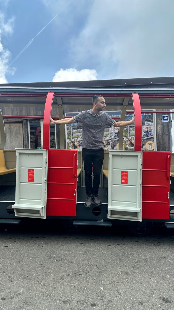 Adil Musa posing between the red doors of a Brienz Rothorn train